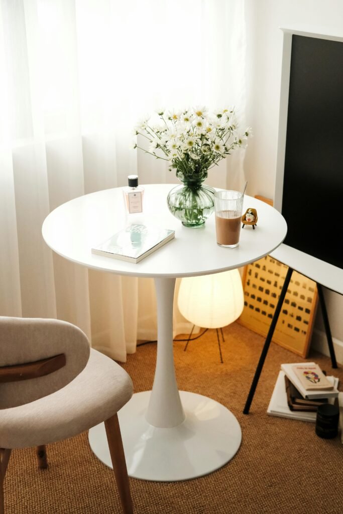 A serene and elegantly arranged table setup with daisies, books, and decor in a stylish room.