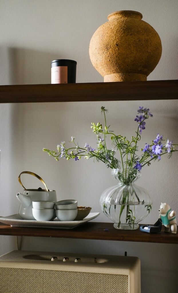 Stylish shelf setup featuring a flower vase, ceramic pot, and tea set in a modern interior.